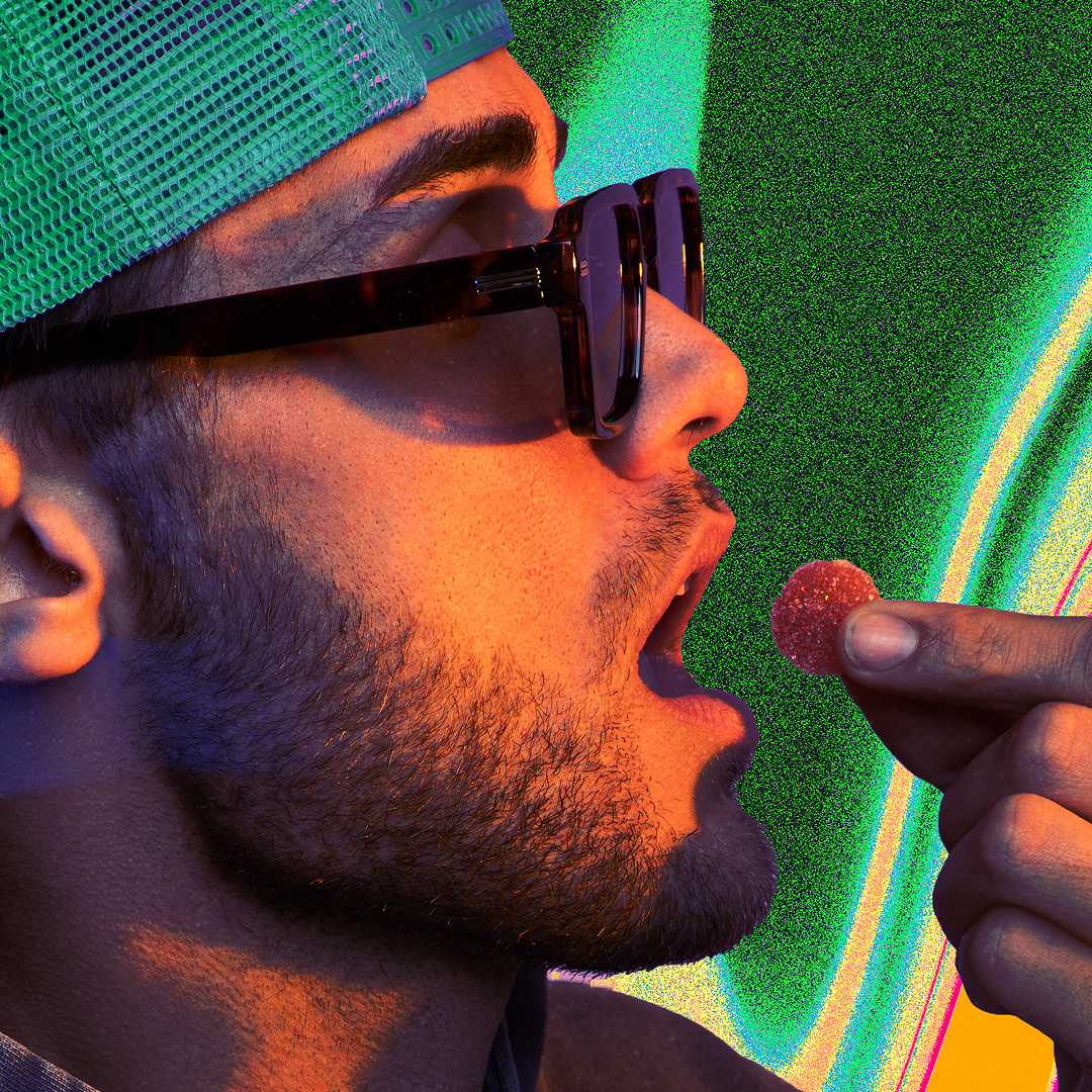 Man in green mesh cap and sunglasses about to eat a red sugar-coated gummy