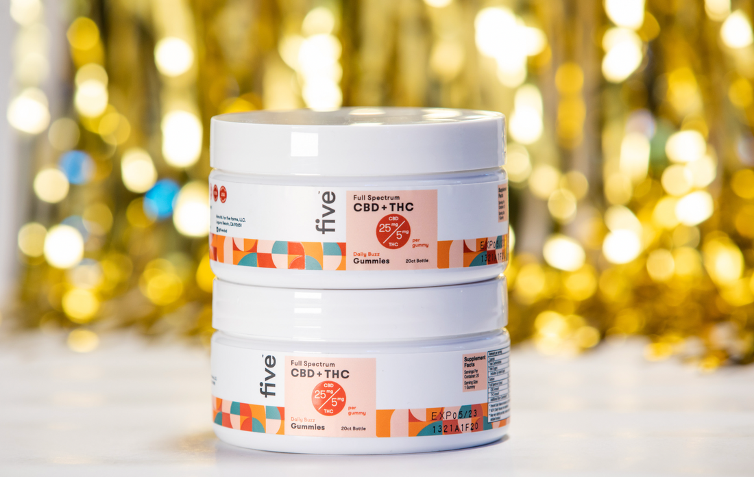 Front view of two stacked Five jars showing Full Spectrum CBD and THC Daily Buzz gummies label with gold bokeh background