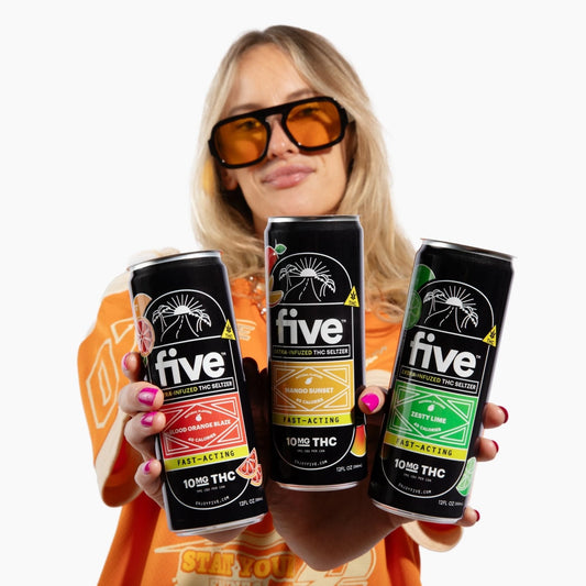 Person holding three Five 10mg THC seltzer cans on white background