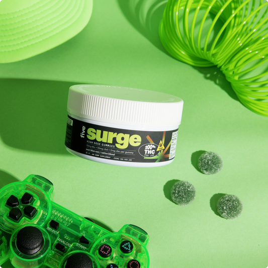 Angled view of Surge high-dose THC gummies jar showing surge label and 200 mg THC badge on green background with controller and three sugar-coated gummies